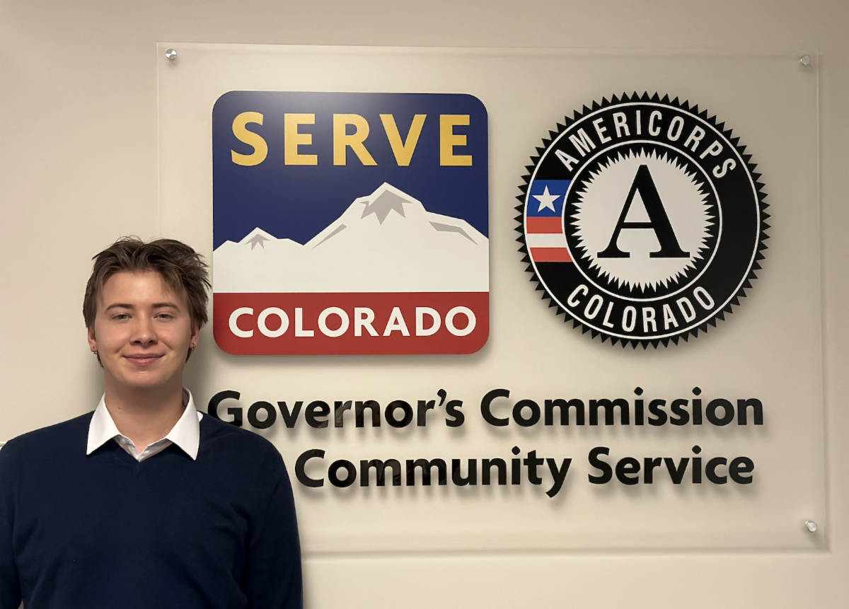 Ben Mattern in front of the Serve Colorado logo and AmeriCorps Colorado logo