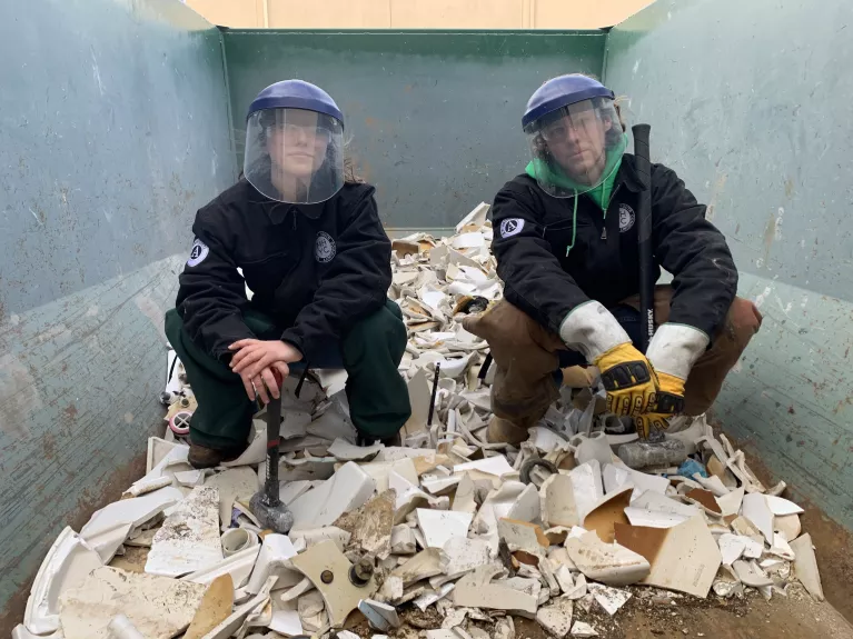 Two members sit on a pile of smashed toilets