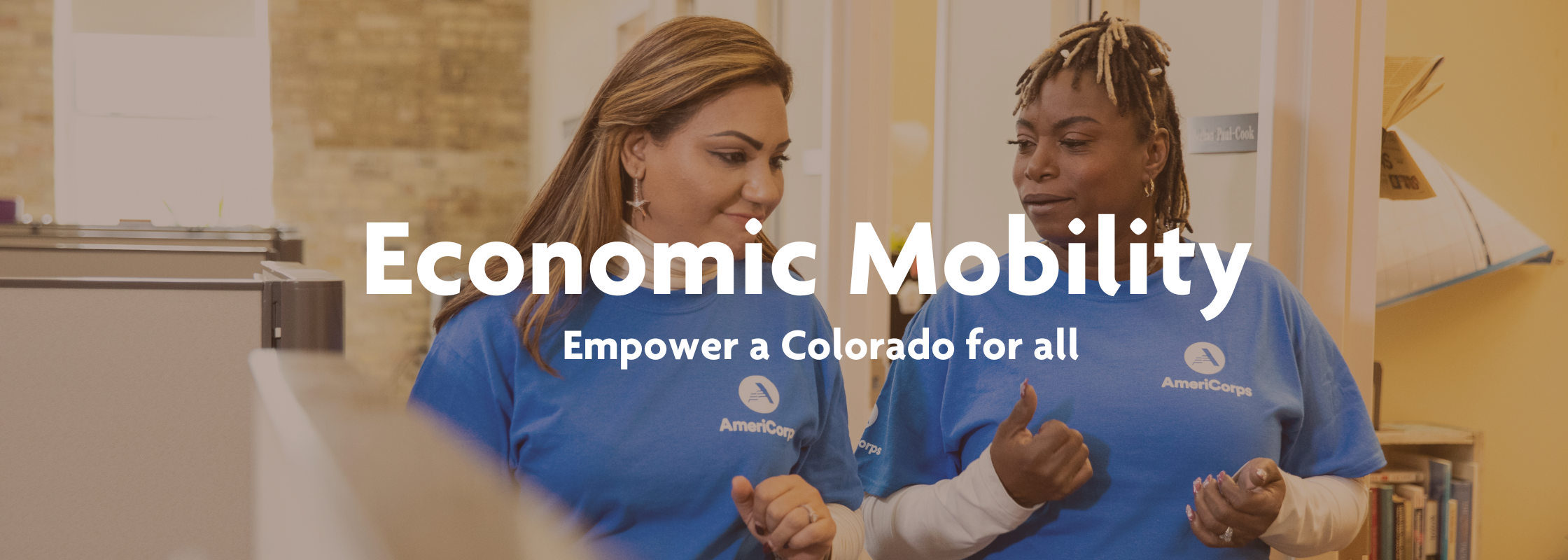 Two women walk side by side and smile in blue AmeriCorps t shirts. The image reads: "Economic Mobility: Empower a Colorado for all" 