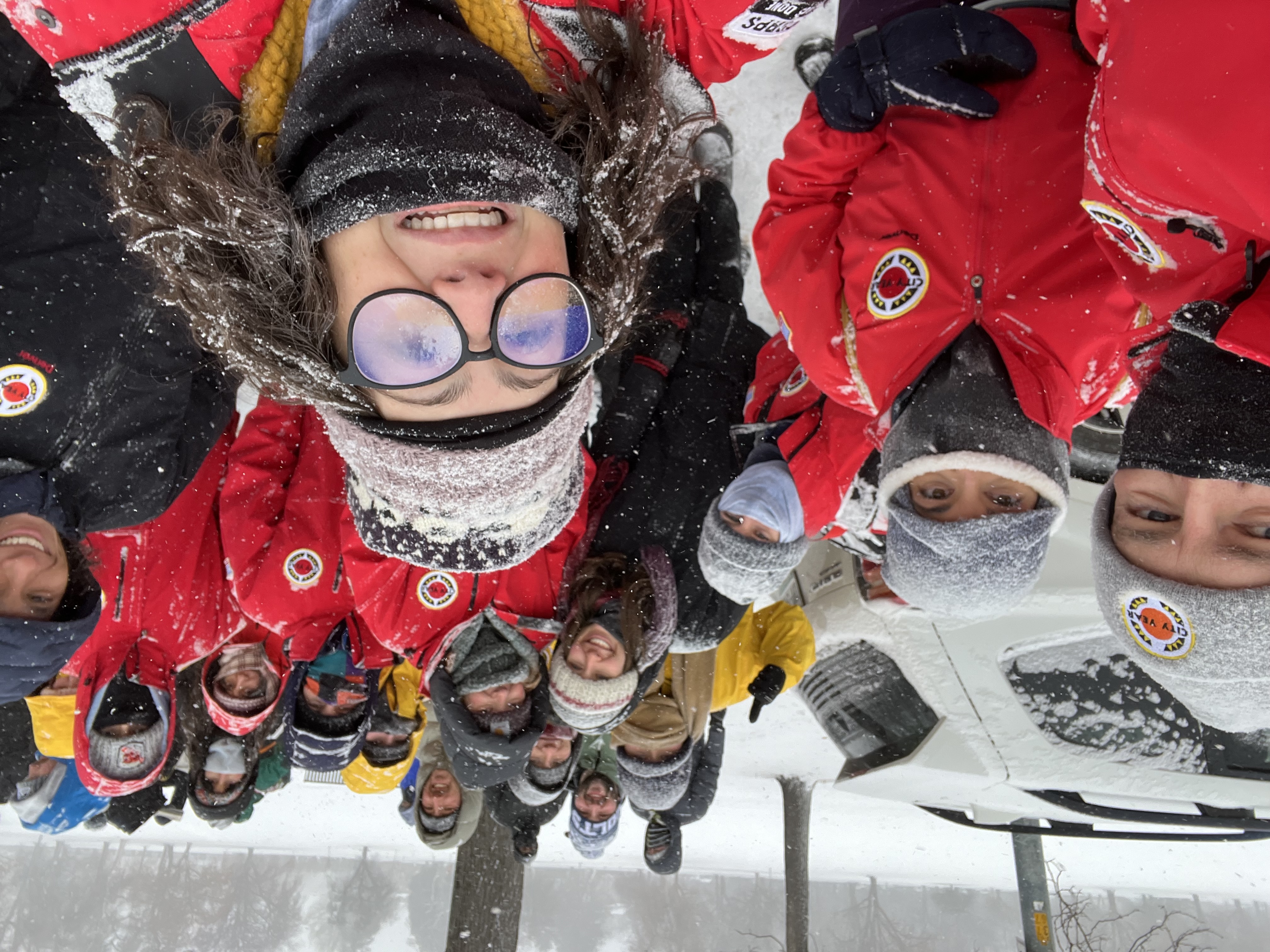 A group of City Year members pose for a selfie in the snow with red jackets on.