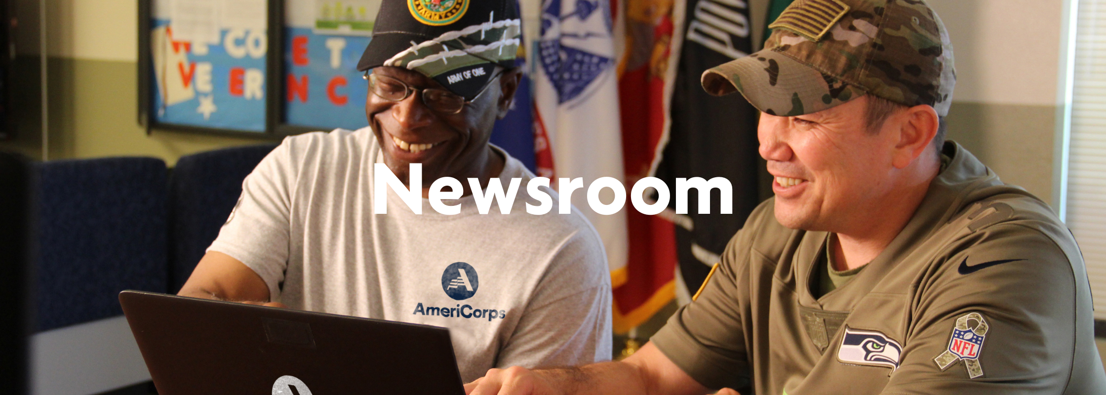 A decorative banner with an AmeriCorps member helping a military member. It reads "newsroom"
